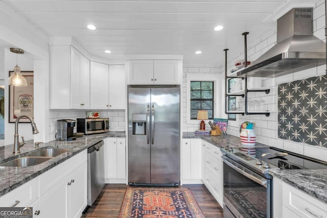 kitchen with stainless steel appliances, wall chimney range hood, a sink, decorative backsplash, and recessed lighting