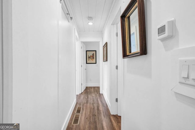 corridor with dark wood-type flooring, baseboards, and attic access