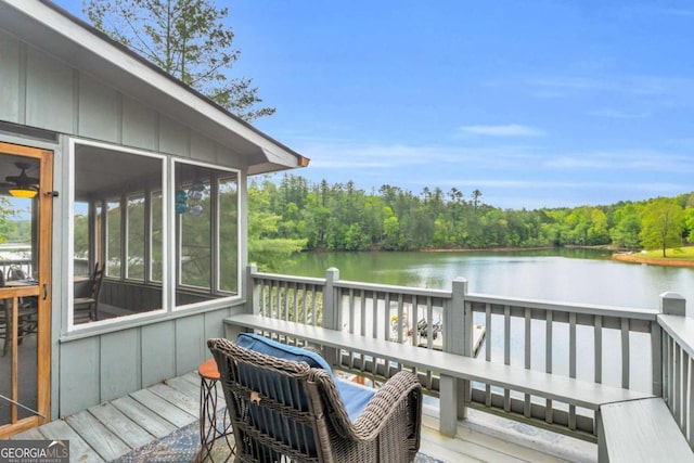 wooden terrace with a water view, a view of trees, and a sunroom