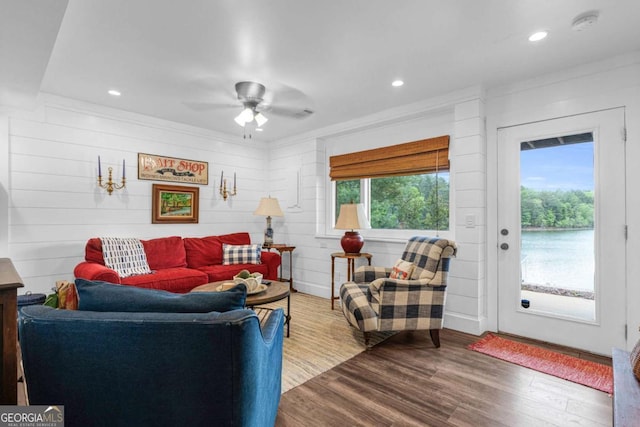 living room with healthy amount of natural light, wood finished floors, ceiling fan, recessed lighting, and wooden walls