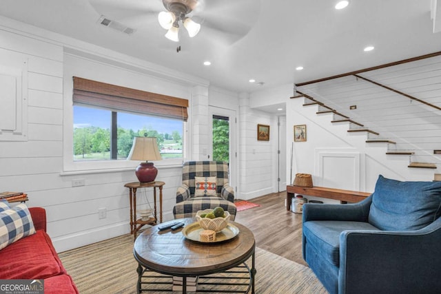 living area with recessed lighting, a ceiling fan, stairs, wood finished floors, and ornamental molding