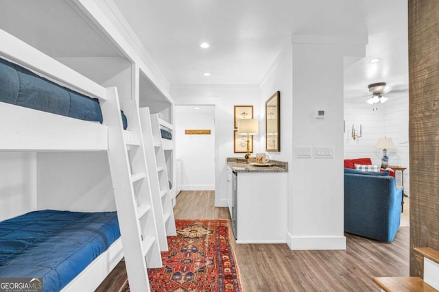bedroom with wood finished floors, baseboards, recessed lighting, and ornamental molding