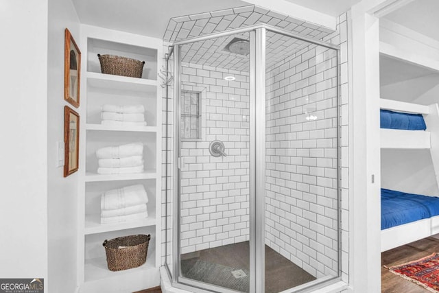 full bath featuring a stall shower, wood finished floors, and built in features
