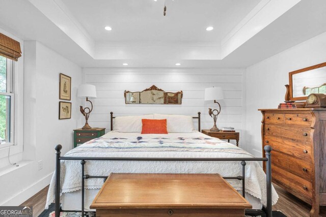 bedroom with wood finished floors, a raised ceiling, recessed lighting, and baseboards