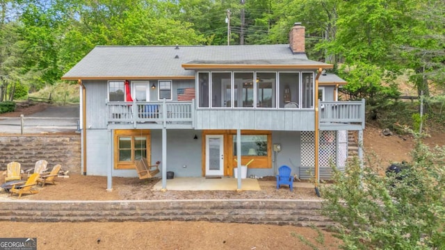 back of house featuring a chimney, a patio area, and a sunroom