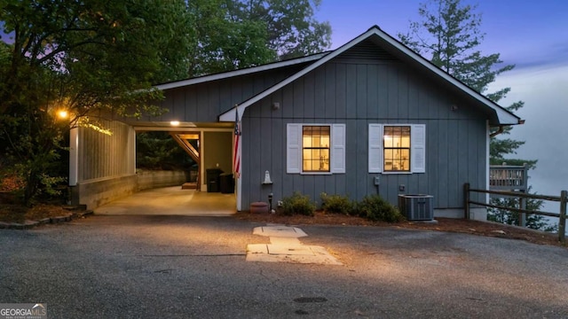 property exterior at dusk with driveway, cooling unit, and an attached carport