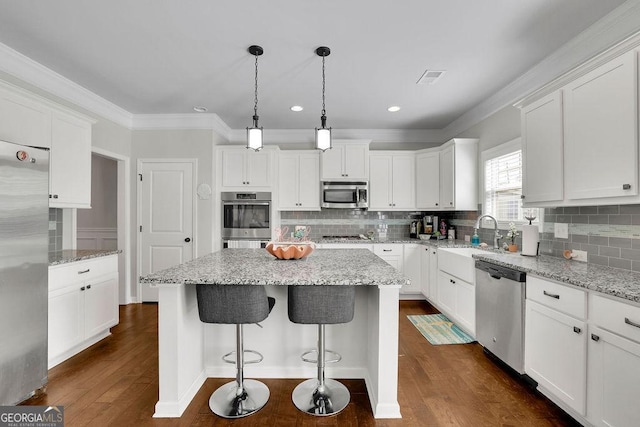 4050 Pleasant Woods Dr, Cumming, GA 30028 - kitchen with stainless steel appliances, a kitchen island, white cabinets, recessed lighting, and ornamental molding