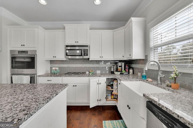 4050 Pleasant Woods Dr, Cumming, GA 30028 - kitchen with appliances with stainless steel finishes, ornamental molding, white cabinetry, dark wood-style flooring, and decorative backsplash
