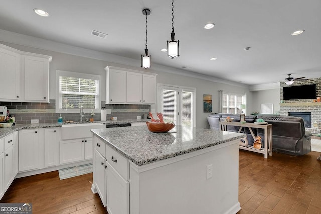 4050 Pleasant Woods Dr, Cumming, GA 30028 - kitchen featuring a sink, ceiling fan, crown molding, a brick fireplace, and decorative backsplash