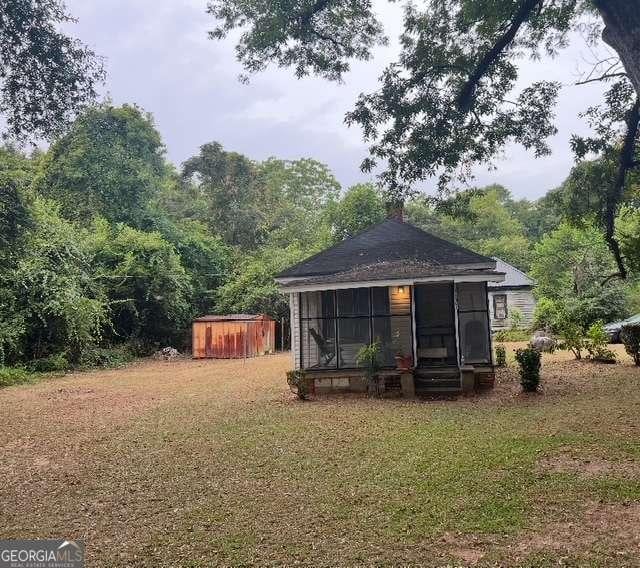 1123 Peach St, Perry, GA 31069 - back of house with a sunroom, a storage unit, an outbuilding, and a yard