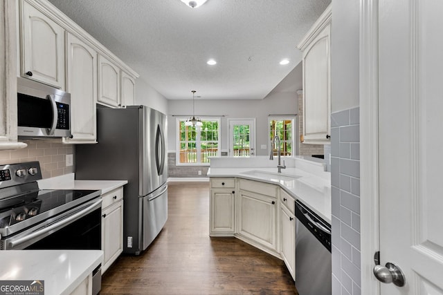 84 Creekside Ct, Zebulon, GA 30295 - kitchen with stainless steel appliances, a sink, dark wood-type flooring, a textured ceiling, and a peninsula