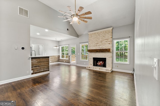84 Creekside Ct, Zebulon, GA 30295 - unfurnished living room with dark wood finished floors, ceiling fan, a brick fireplace, plenty of natural light, and high vaulted ceiling