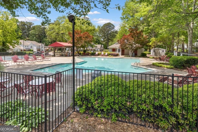 community pool with fence, a patio area, an outdoor structure, and a shed