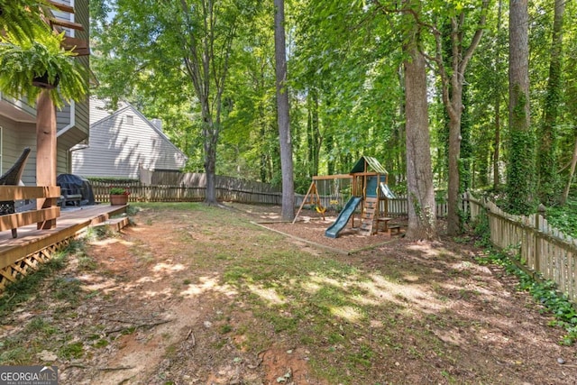 fenced backyard featuring a playground and a deck