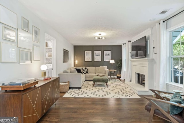 living room with wood finished floors, a fireplace with raised hearth, and a chandelier
