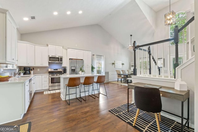 kitchen featuring stainless steel appliances, high vaulted ceiling, a center island, white cabinets, and light countertops