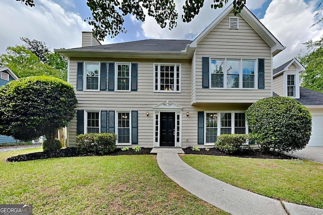 view of front of property featuring a chimney, a garage, and a front lawn