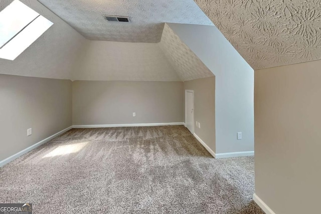 bonus room featuring a textured ceiling, carpet flooring, lofted ceiling, baseboards, and a skylight