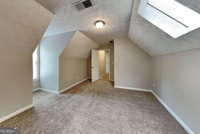 additional living space featuring a textured ceiling, carpet floors, vaulted ceiling, and baseboards