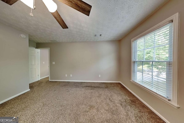 carpeted spare room featuring plenty of natural light, a textured ceiling, baseboards, and ceiling fan