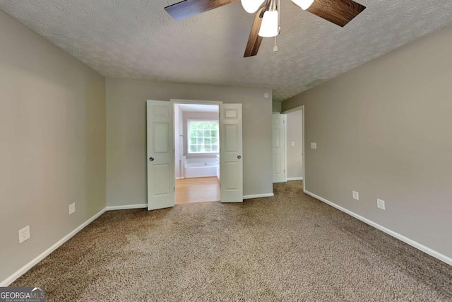 unfurnished bedroom featuring a textured ceiling, baseboards, carpet floors, and a ceiling fan