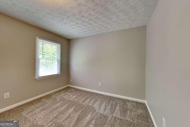 empty room featuring a textured ceiling, carpet, and baseboards