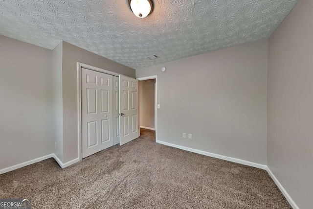 unfurnished bedroom featuring carpet flooring, a textured ceiling, a closet, and baseboards
