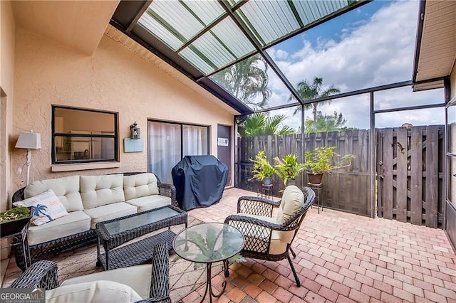 view of patio with area for grilling, outdoor lounge area, fence, and a lanai