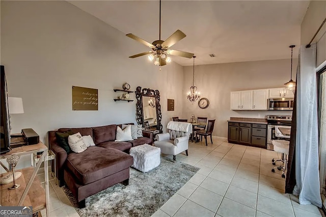 living room with a ceiling fan, high vaulted ceiling, light tile patterned flooring, and a chandelier