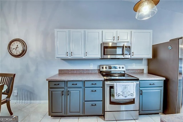 kitchen featuring stainless steel appliances, white cabinetry, light tile patterned flooring, baseboards, and blue cabinetry