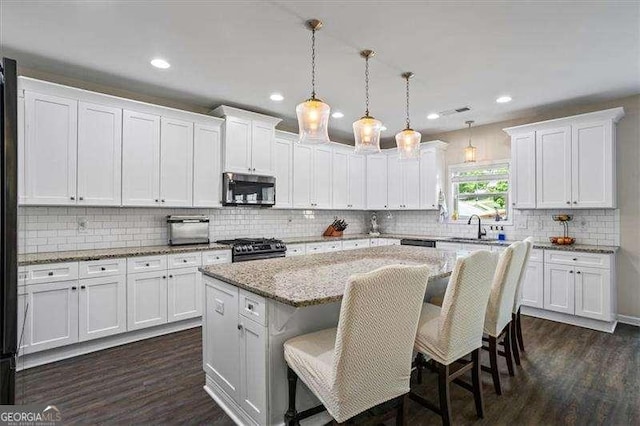 380 Longwood Pl, Dallas, GA 30132 - kitchen with stainless steel microwave, a kitchen island, white cabinetry, gas stove, and recessed lighting