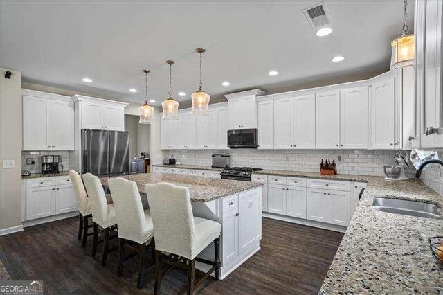 380 Longwood Pl, Dallas, GA 30132 - kitchen featuring stainless steel appliances, a sink, a kitchen island, backsplash, and white cabinetry