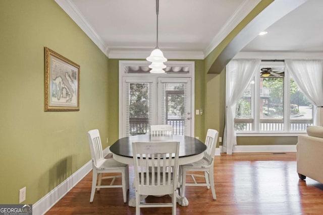 dining room with baseboards, crown molding, wood finished floors, and ceiling fan