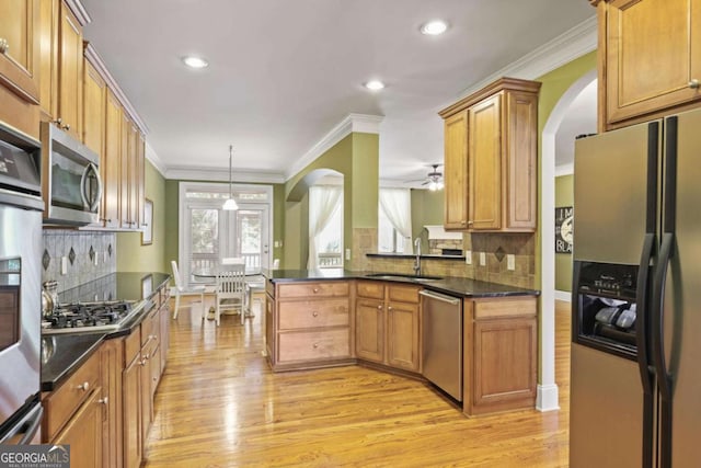 kitchen with appliances with stainless steel finishes, arched walkways, light wood-style floors, crown molding, and recessed lighting