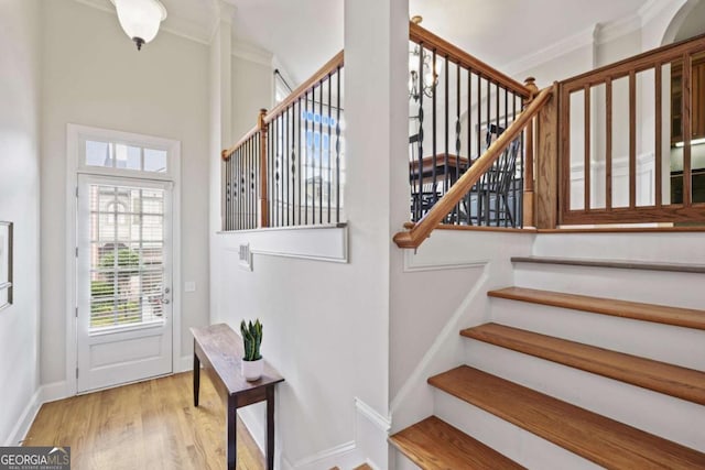 stairway with ornamental molding, plenty of natural light, wood finished floors, and baseboards