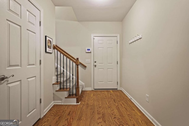 foyer entrance with wood finished floors, baseboards, and stairway