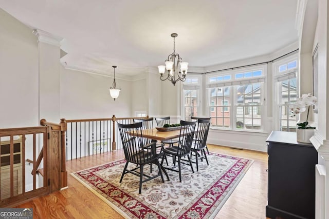 dining area featuring a chandelier, light wood-style flooring, and crown molding