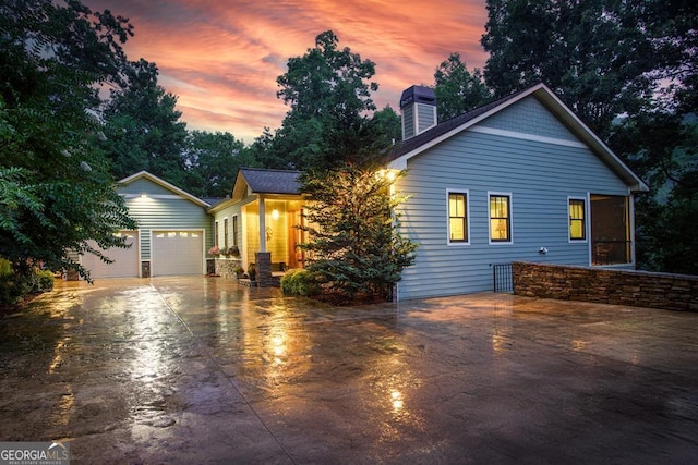 view of front of property featuring a chimney, driveway, and an attached garage