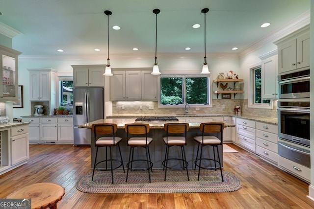 kitchen featuring stainless steel appliances, a warming drawer, a sink, plenty of natural light, and ornamental molding