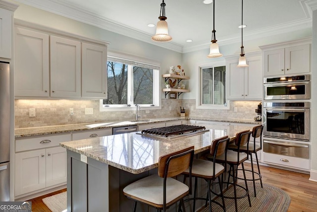 kitchen with a warming drawer, stainless steel appliances, a sink, hanging light fixtures, and a kitchen bar