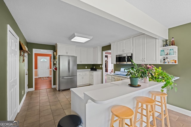 233 Clark Rd, Midville, GA 30441 - kitchen with stainless steel appliances, a textured ceiling, a breakfast bar, light countertops, and white cabinets