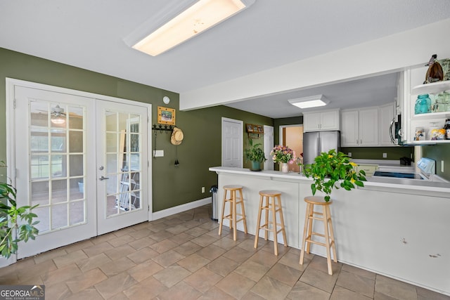 233 Clark Rd, Midville, GA 30441 - kitchen with appliances with stainless steel finishes, a peninsula, french doors, white cabinets, and a kitchen breakfast bar