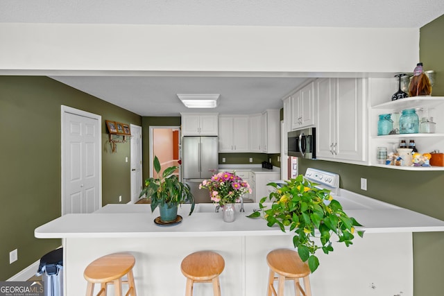 233 Clark Rd, Midville, GA 30441 - kitchen with appliances with stainless steel finishes, a peninsula, a breakfast bar, light countertops, and white cabinetry