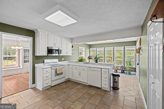 233 Clark Rd, Midville, GA 30441 - kitchen with white appliances, a peninsula, light countertops, white cabinetry, and a textured ceiling