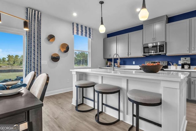 508 Regency Trl, Acworth, GA 30102 - kitchen featuring appliances with stainless steel finishes, light wood-style floors, a kitchen island with sink, a sink, and light countertops