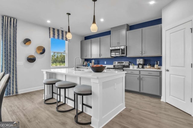 508 Regency Trl, Acworth, GA 30102 - kitchen with appliances with stainless steel finishes, gray cabinetry, light wood-style floors, an island with sink, and light countertops