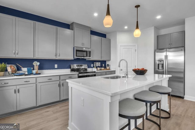 508 Regency Trl, Acworth, GA 30102 - kitchen featuring stainless steel appliances, a sink, gray cabinetry, a breakfast bar, and light wood-style flooring