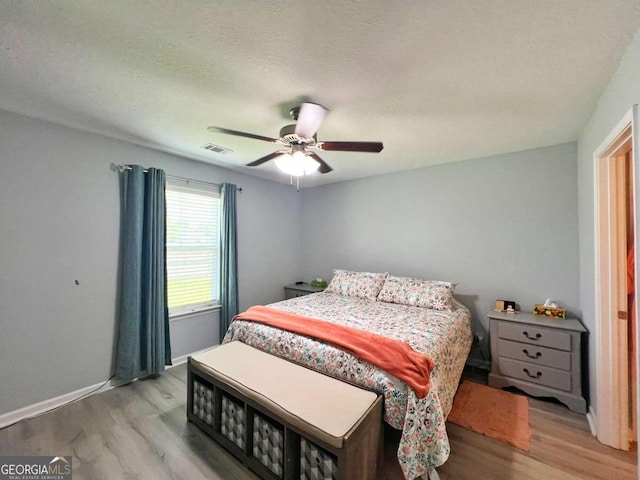 bedroom with wood finished floors, a ceiling fan, a textured ceiling, and baseboards