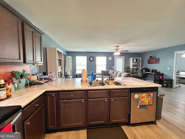 kitchen featuring stainless steel appliances, light wood-style flooring, open floor plan, a ceiling fan, and light countertops
