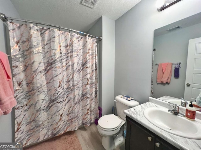 bathroom featuring wood finished floors, a textured ceiling, vanity, toilet, and curtained shower